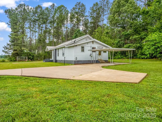 a view of a house next to a big yard with large trees