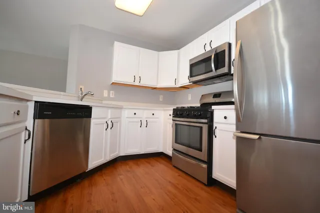 a kitchen with cabinets stainless steel appliances and wooden floor