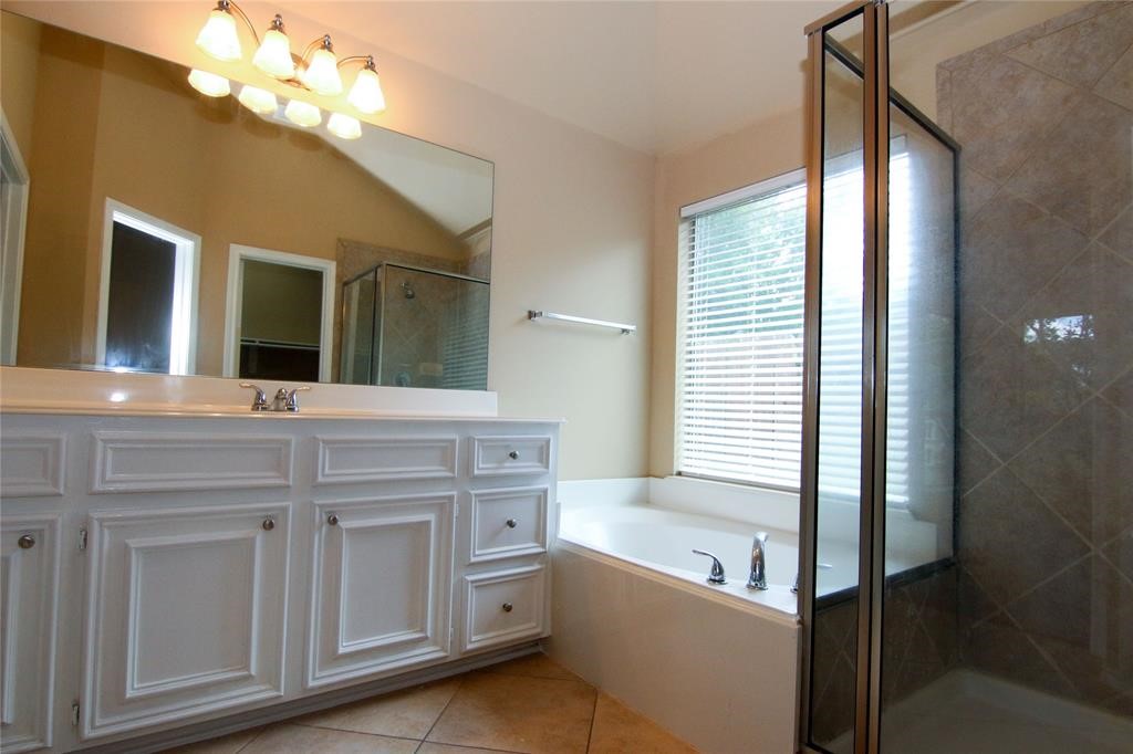27431 Rebecca Field Lane Spring, TX 77386 - Photo 18 of 26 a bathroom with a tub a double vanity sink and a mirror