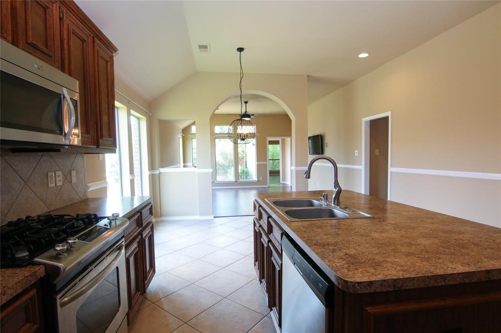 27431 Rebecca Field Lane Spring, TX 77386 - Photo 8 of 26 a kitchen with granite countertop a stove a sink and a microwave