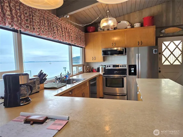 a kitchen with stainless steel appliances a stove a refrigerator and a dining table