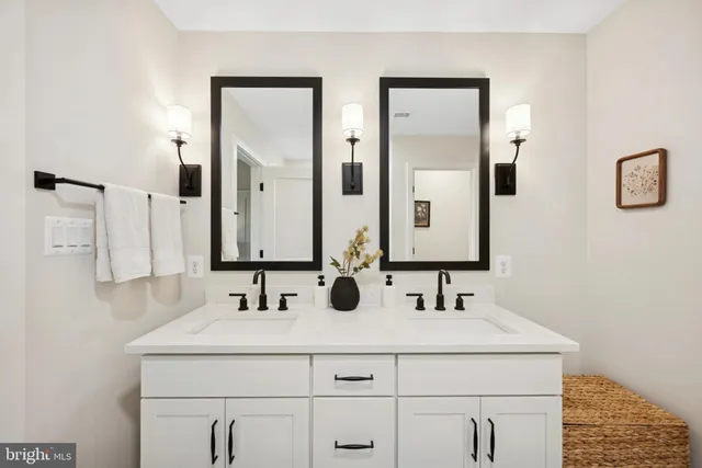 a bathroom with double vanity sink and two mirror