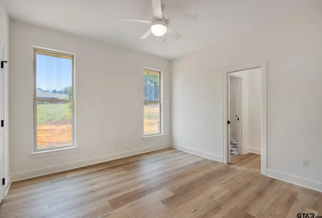 an empty room with wooden floor and windows