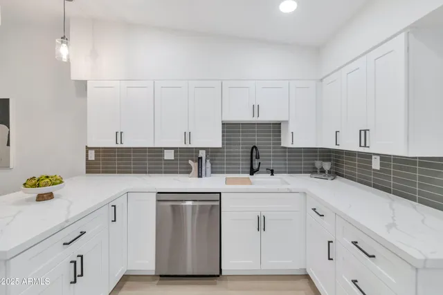 a kitchen with a sink dishwasher and white cabinets