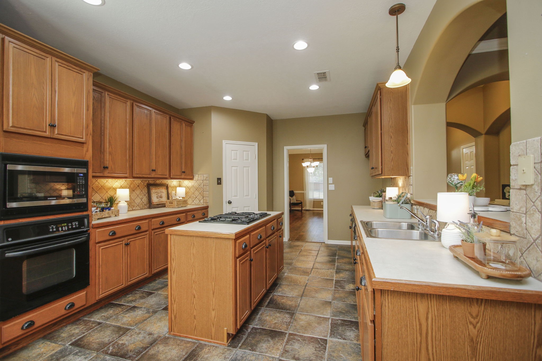 9203 Memorial Pines Way Spring, TX 77379 - Photo 17 of 45 This kitchen features warm wooden cabinetry with ample storage, a central island with a cooktop, and a dual sink.