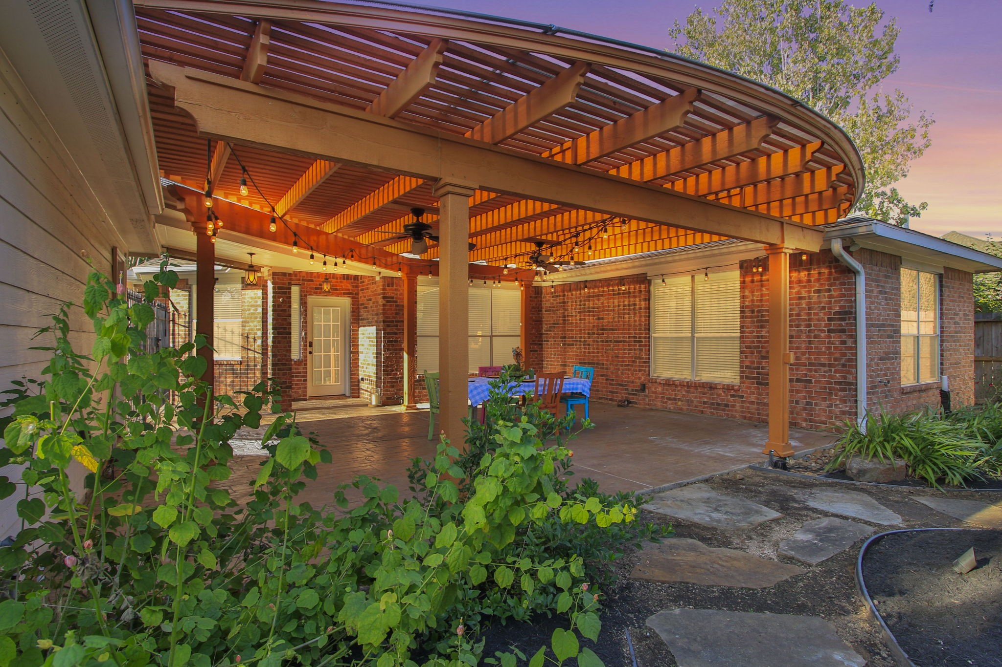 9203 Memorial Pines Way Spring, TX 77379 - Photo 2 of 45 Beautiful covered patio with custom pergola, string lights, and ceiling fans—perfect for outdoor dining and entertaining. Stamped-concrete flooring and lush landscaping create a relaxing backyard retreat.