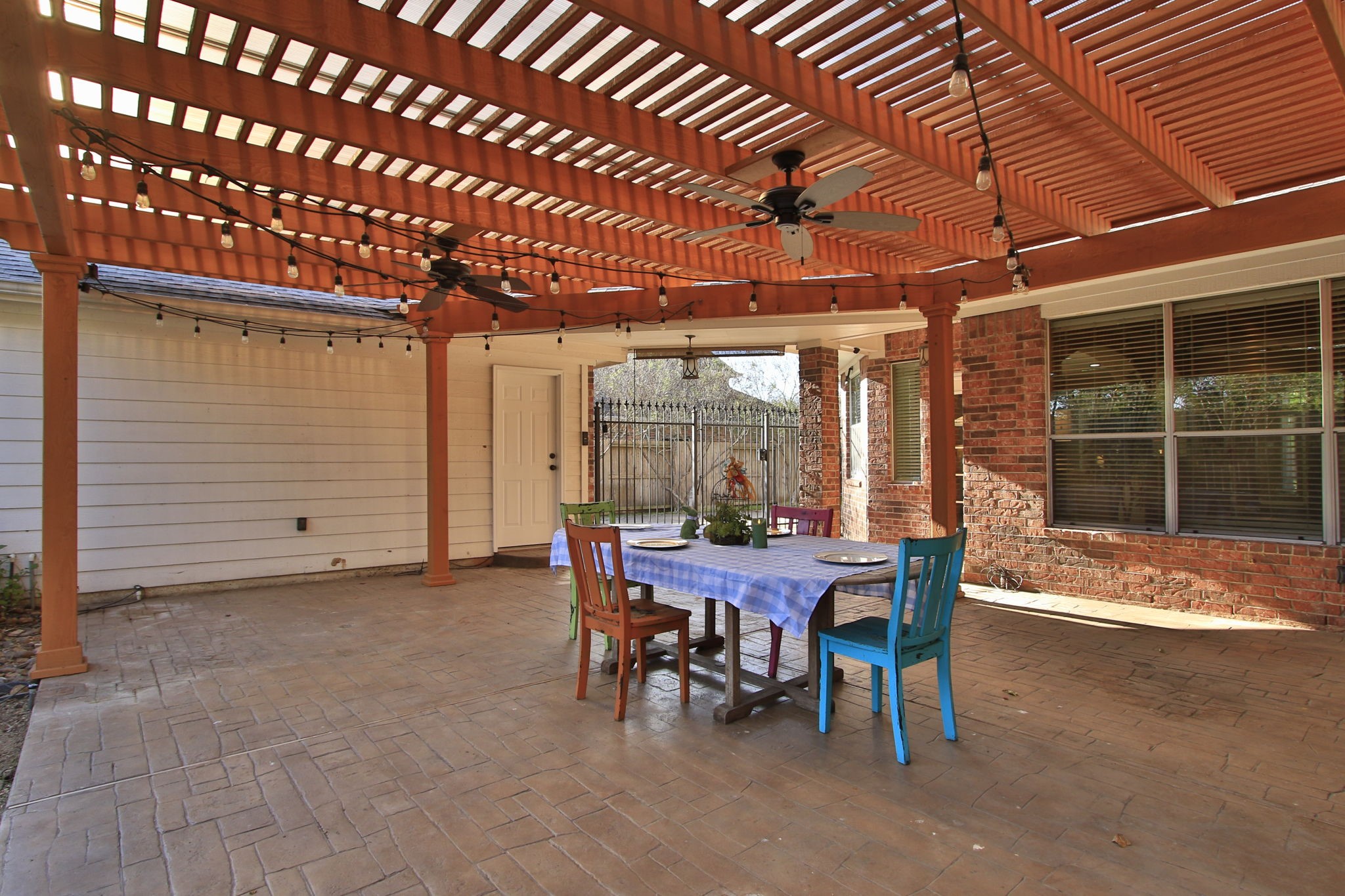 9203 Memorial Pines Way Spring, TX 77379 - Photo 38 of 45 This photo showcases a spacious patio with a wooden pergola, featuring ceiling fans and string lights.