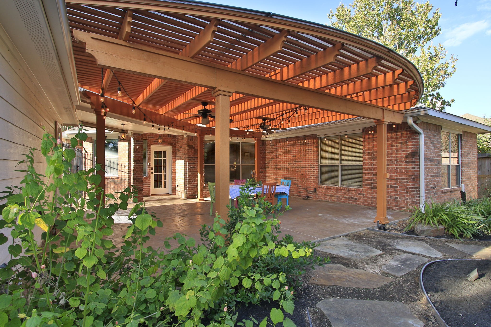 9203 Memorial Pines Way Spring, TX 77379 - Photo 39 of 45 The patio is always shaded and is perfect for outdoor entertaining, with a cozy dining area, string lights for ambiance, and surrounding greenery for a touch of nature.