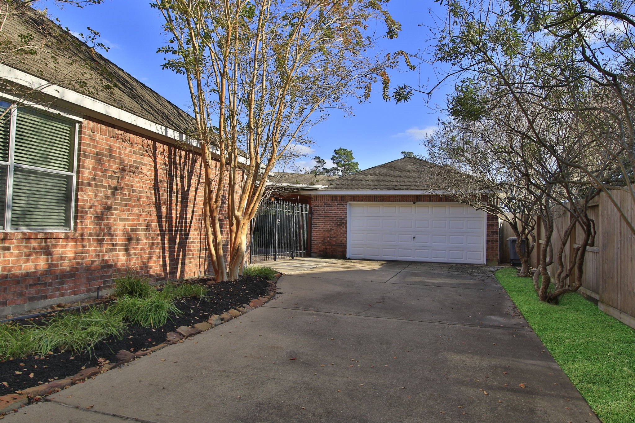 9203 Memorial Pines Way Spring, TX 77379 - Photo 5 of 45 Spacious driveway leading to a two-car garage. A wooden fence adds privacy, and the overall setting is clean and well-maintained.