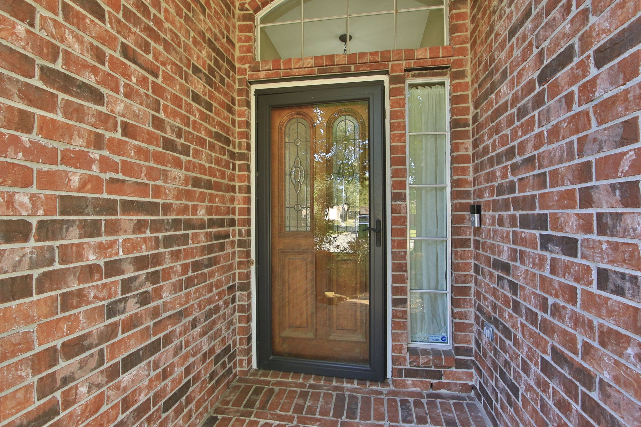 9203 Memorial Pines Way Spring, TX 77379 - Photo 7 of 45 Charming brick entryway featuring a wood door with decorative glass panels, flanked by a tall, narrow window.