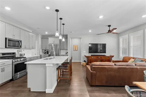 a living room with stainless steel appliances kitchen island a flat screen tv and a refrigerator