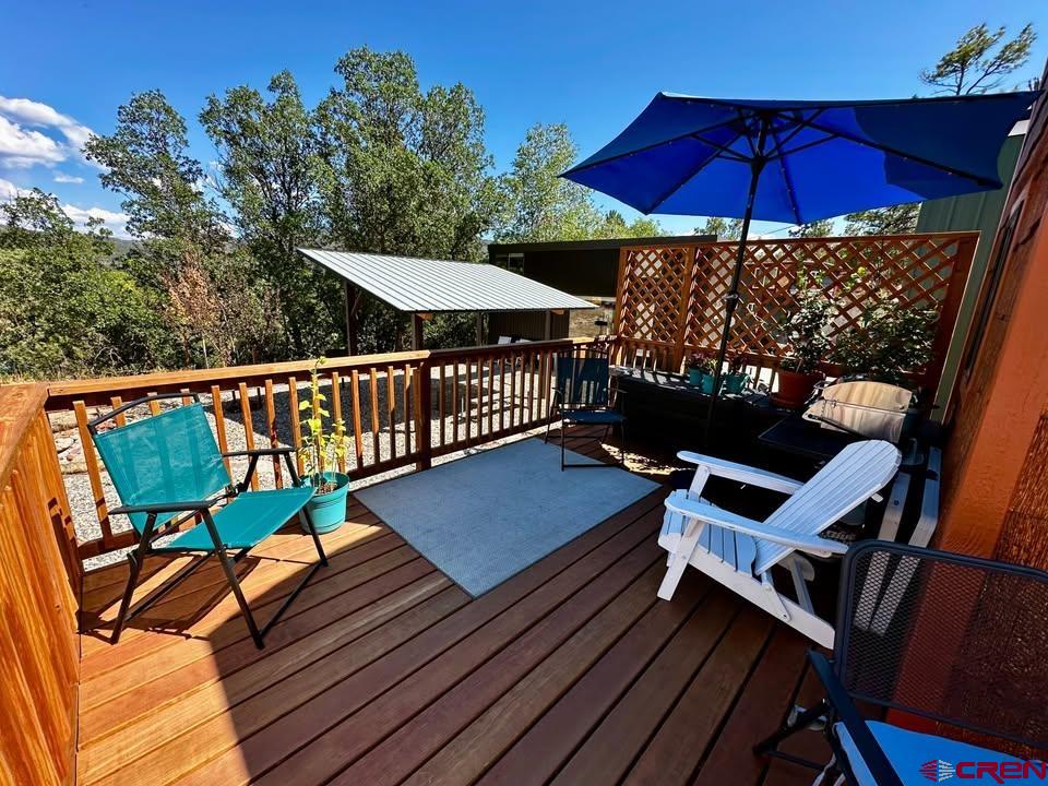 90 Animas View Drive, Unit 5 Durango, CO 81301 - Photo 3 of 30 a view of a roof deck with table and chairs under an umbrella with wooden floor