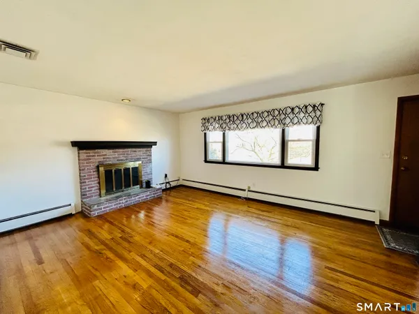 an empty room with wooden floor and fireplace