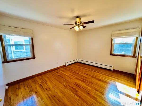 a view of empty room with wooden floor and fan