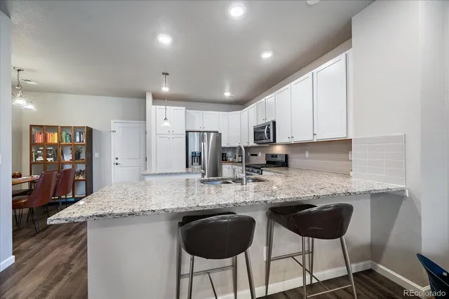 a kitchen with stainless steel appliances granite countertop a stove a sink a refrigerator and chairs