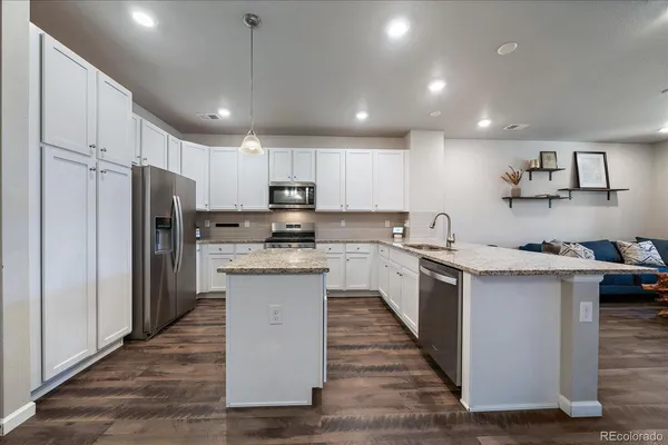 a kitchen with stainless steel appliances granite countertop a sink refrigerator and cabinets