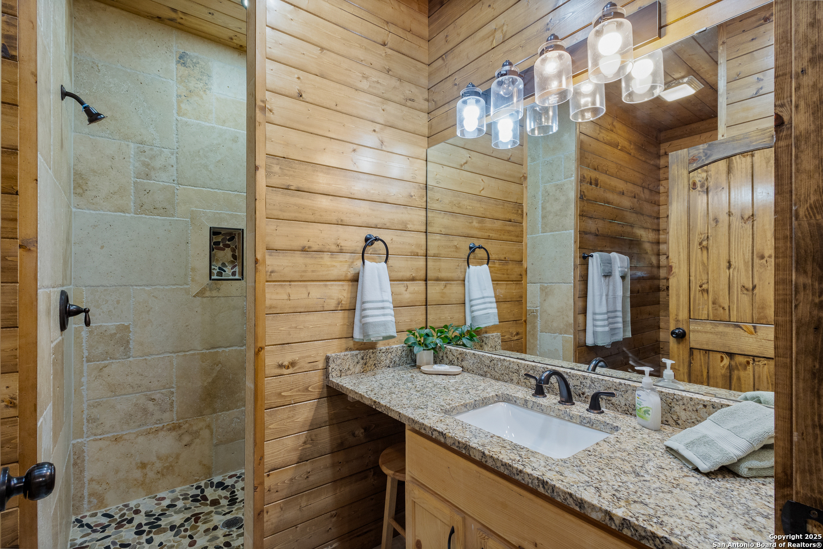 370 Johnny Seibert Rio Frio, TX 78873 - Photo 19 of 40 a bathroom with a granite countertop sink a large mirror and shower