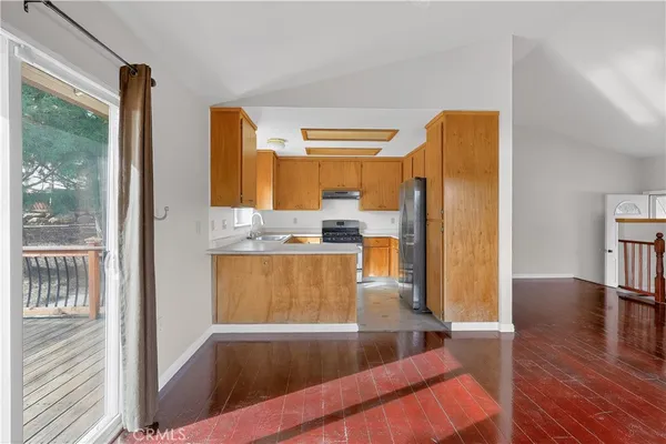 a kitchen with stainless steel appliances granite countertop a refrigerator a stove and a sink with wooden floor