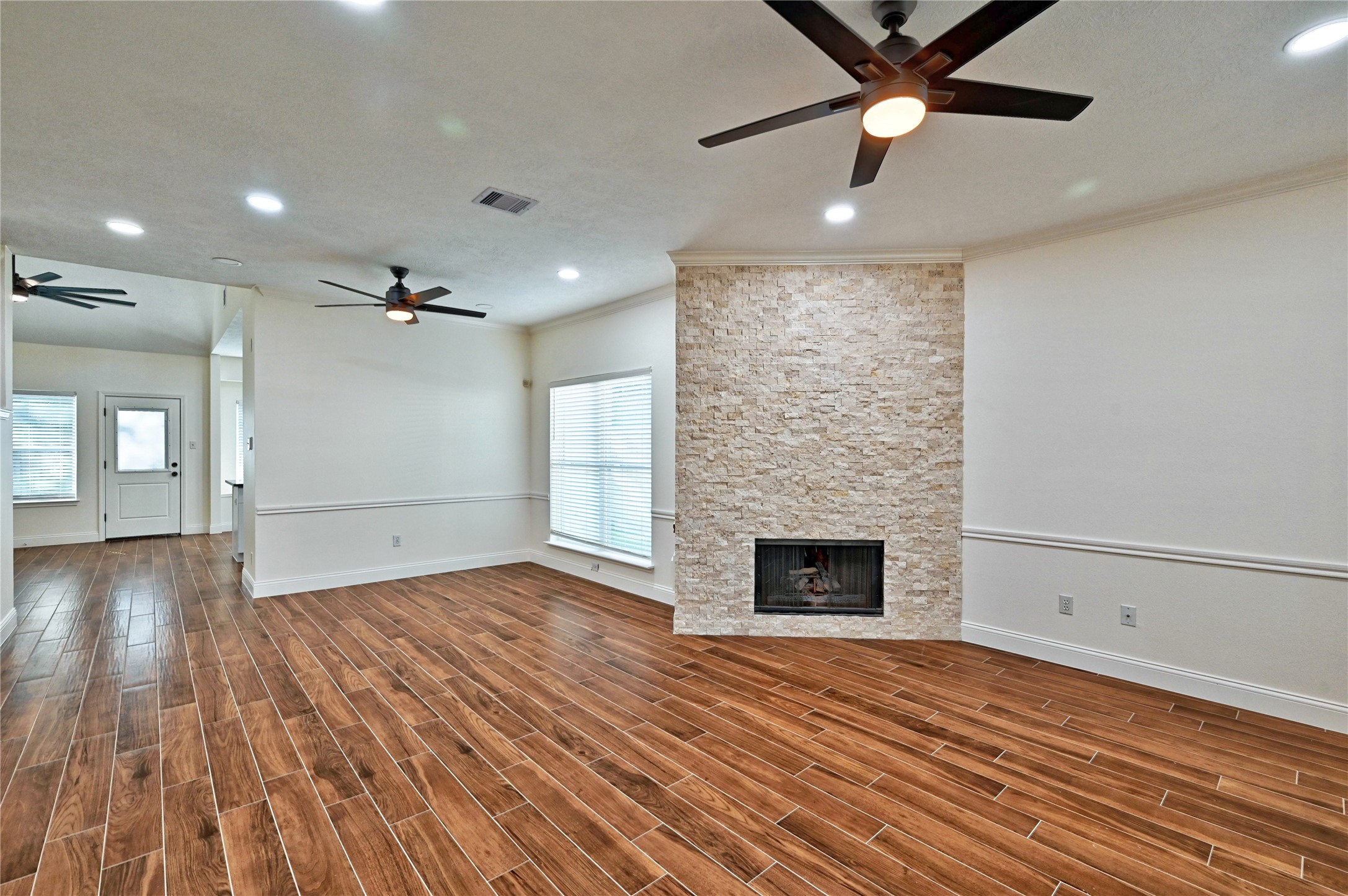 17907 Pelican Way Road Houston, TX 77084 - Photo 6 of 38 an empty room with wooden floor a ceiling fan a fireplace and windows