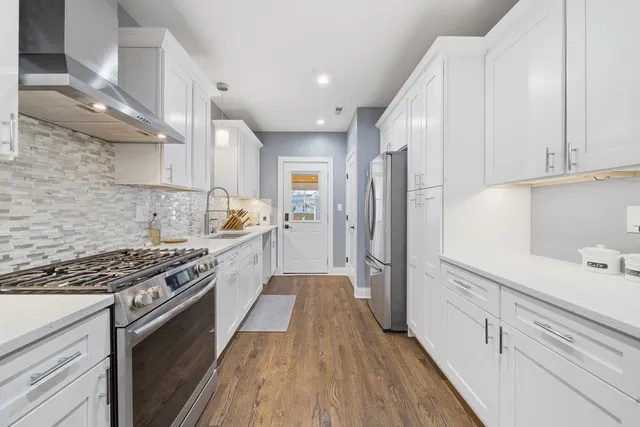 a kitchen with stainless steel appliances a sink dishwasher stove refrigerator and cabinets with wooden floor