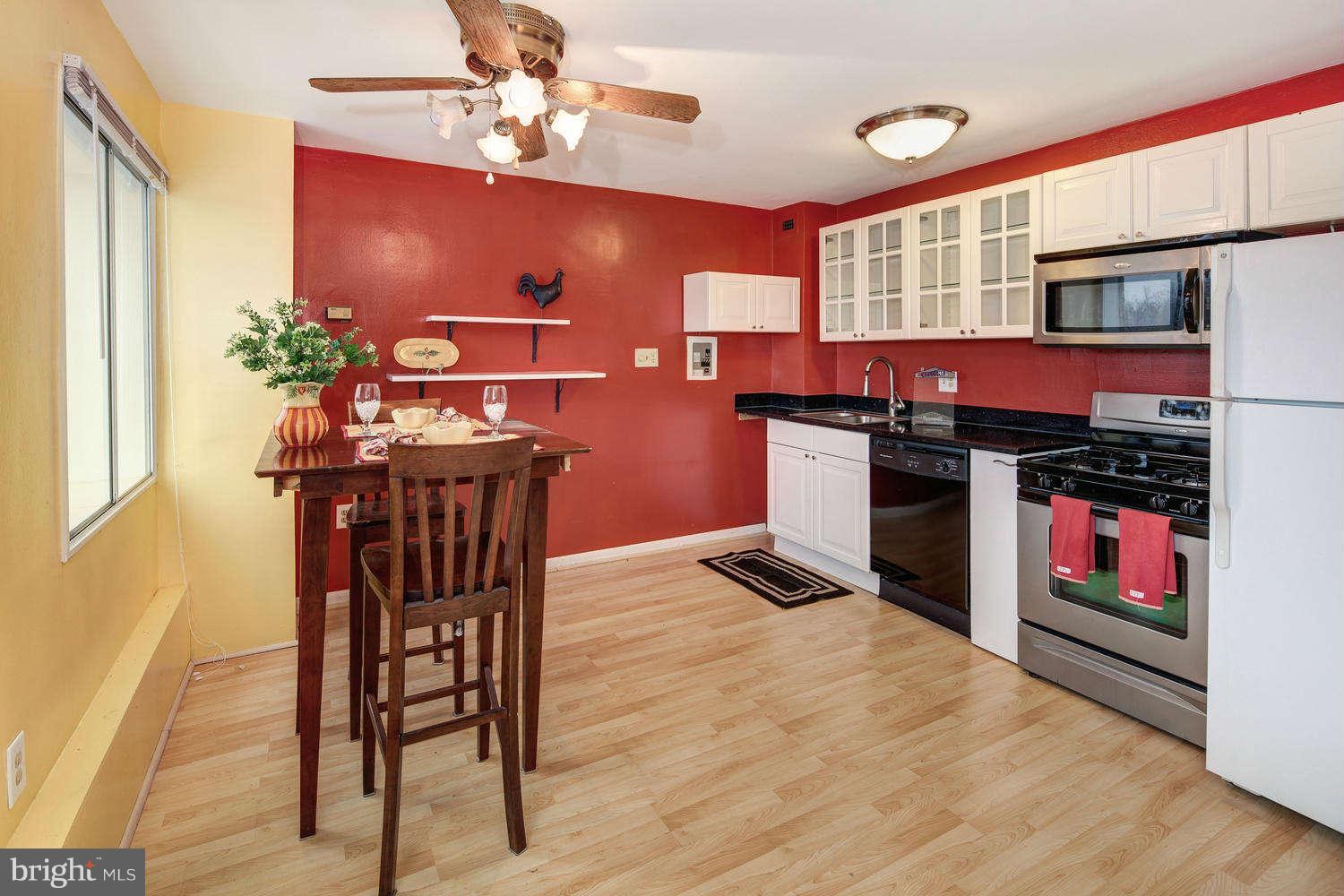 1300 South Arlington Ridge Road, Unit 304 Arlington, VA 22202 - Photo 7 of 19 a kitchen with stainless steel appliances granite countertop a stove a refrigerator a oven a dining table and chairs with wooden floor