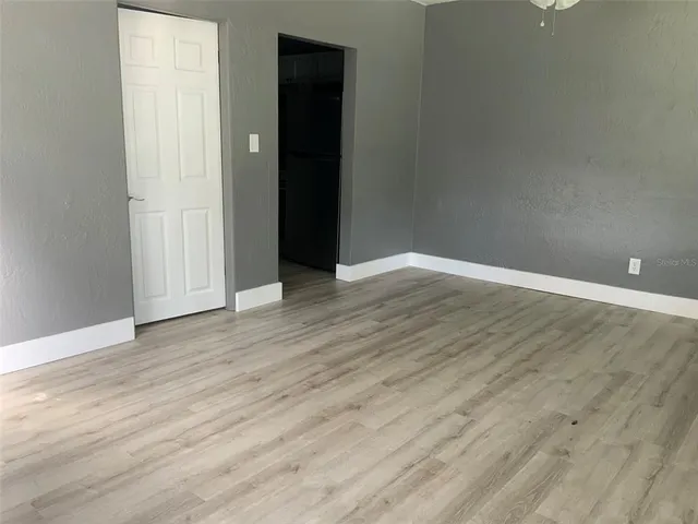 a view of an empty room with wooden floor and closet