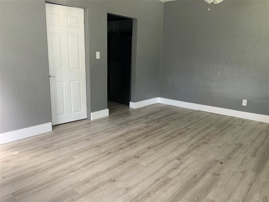 a view of an empty room with wooden floor and closet