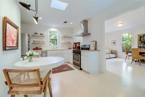 a kitchen with stainless steel appliances granite countertop a stove a sink a dining table and chairs