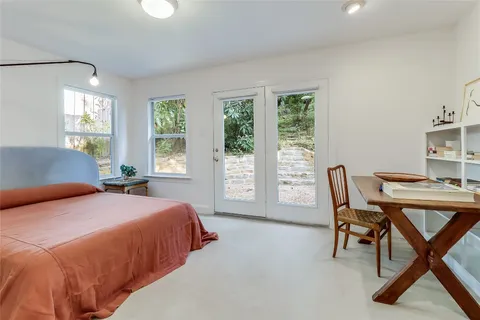 a bedroom with a bed a large window and a computer on the table