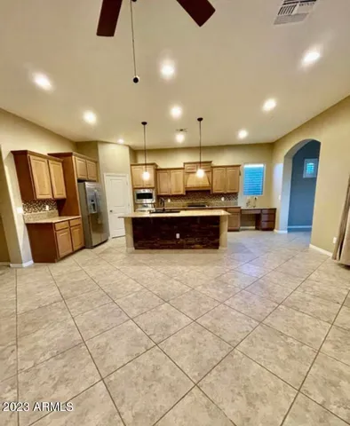 a large kitchen with stainless steel appliances kitchen island granite countertop a refrigerator and a stove top oven