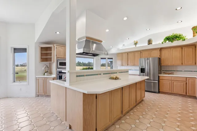 a large kitchen with kitchen island granite countertop a stove a sink a dining table and chairs