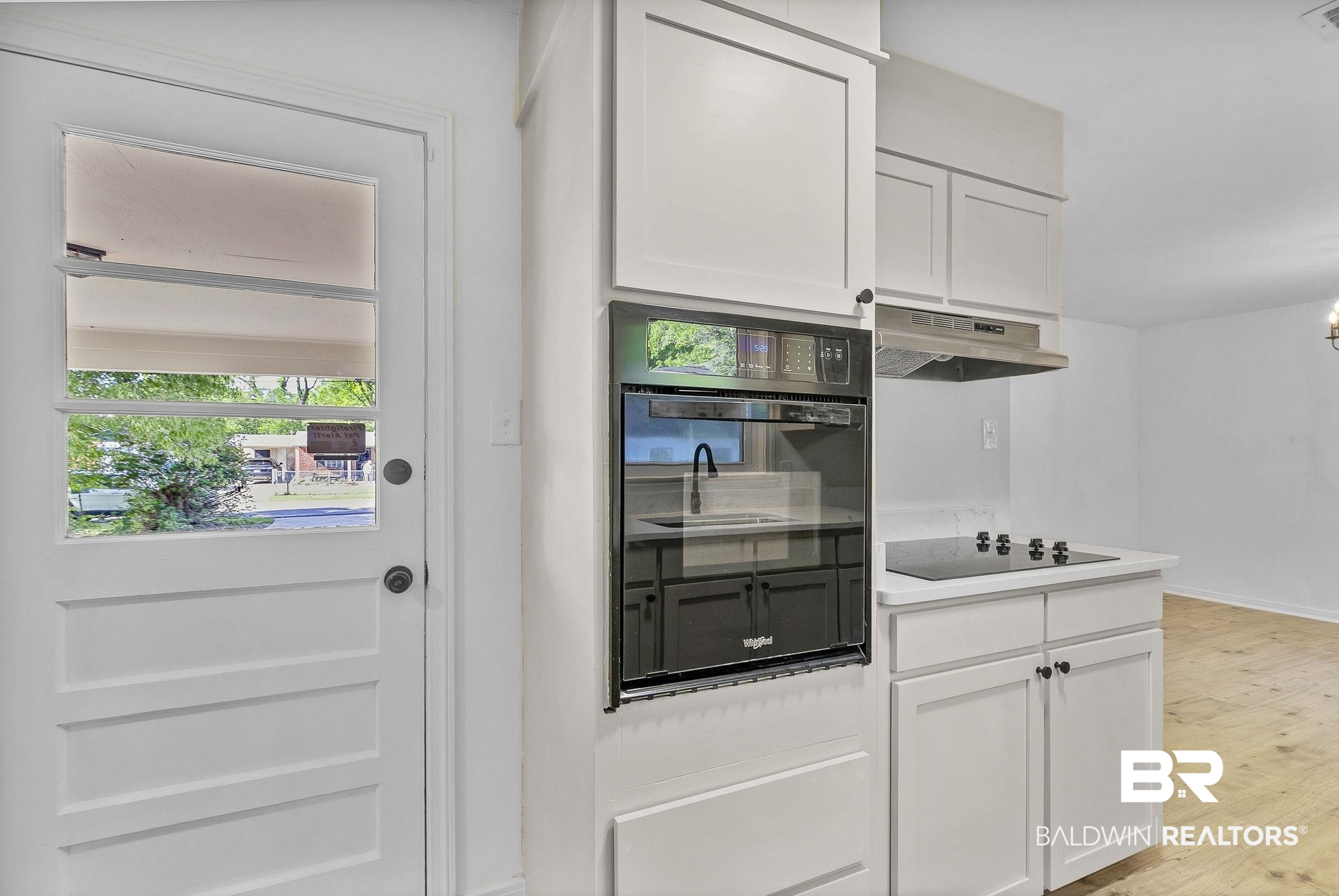 203 Anderson Road Saraland, AL 36571 - Photo 16 of 48 Kitchen with white cabinetry, under cabinet range hood, visible vents, light wood finished floors, and black appliances