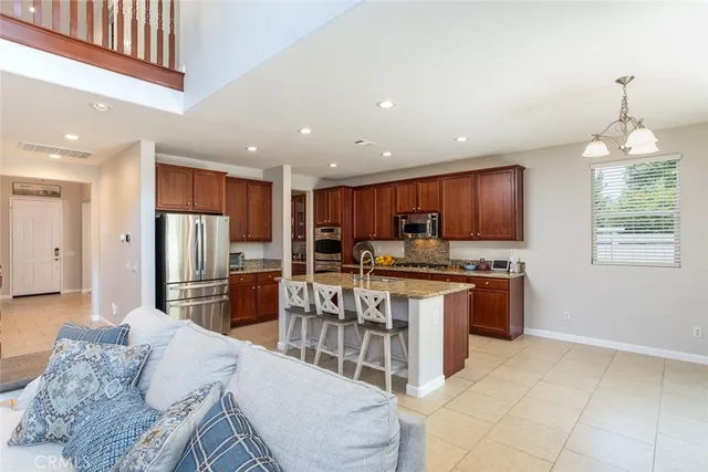 a kitchen with stainless steel appliances kitchen island granite countertop a refrigerator a stove a sink a dining table and chairs with wooden floor