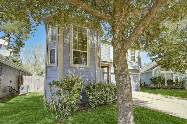 a view of a brick house with a yard and large trees