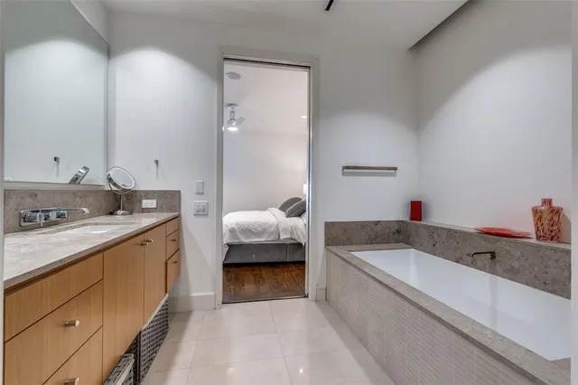 a bathroom with a granite countertop tub sink and mirror