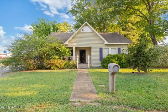 a front view of a house with garden and plants