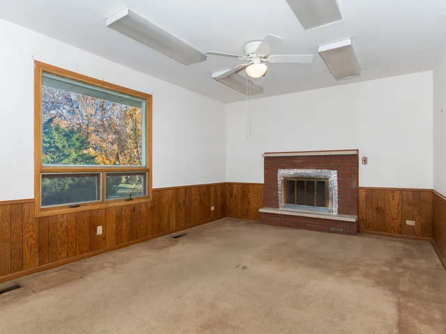 an empty room with fireplace fan and windows