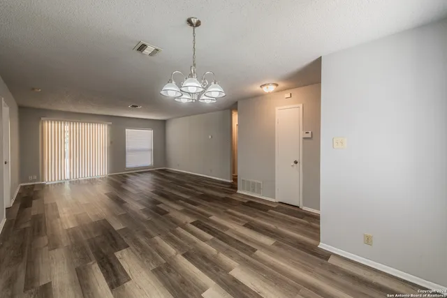 a view of empty room with wooden floor and chandelier