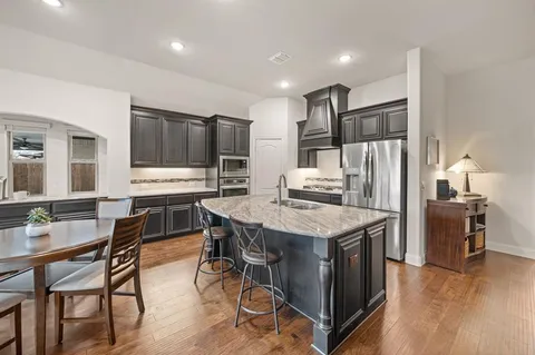 a kitchen with stainless steel appliances kitchen island granite countertop a table chairs stove and refrigerator