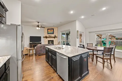 a open kitchen with stainless steel appliances granite countertop a stove top oven a sink a dining table and chairs