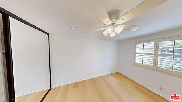 a view of an empty room with windows and chandelier fan