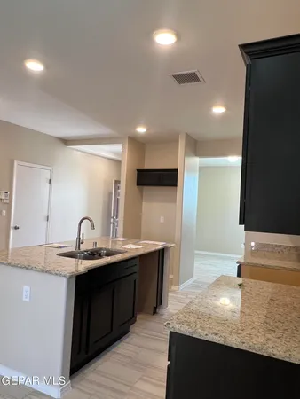 a kitchen with kitchen island granite countertop a sink and cabinets
