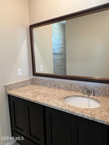 a bathroom with a granite countertop sink and a mirror