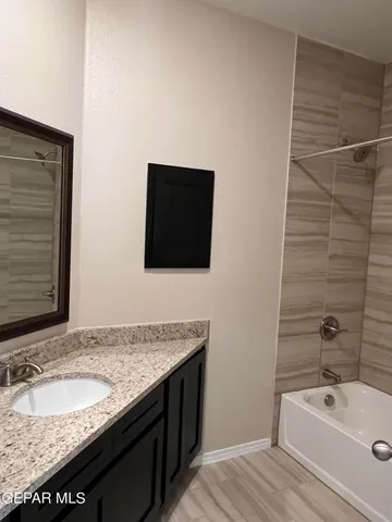 a bathroom with a granite countertop sink and a bathtub