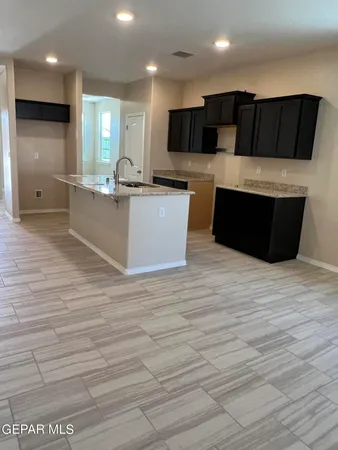 a large white kitchen with kitchen island granite countertop a large counter top stainless steel appliances and cabinets