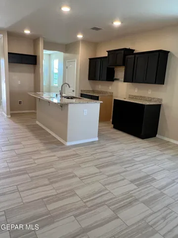 a large white kitchen with kitchen island granite countertop a large counter top stainless steel appliances and cabinets
