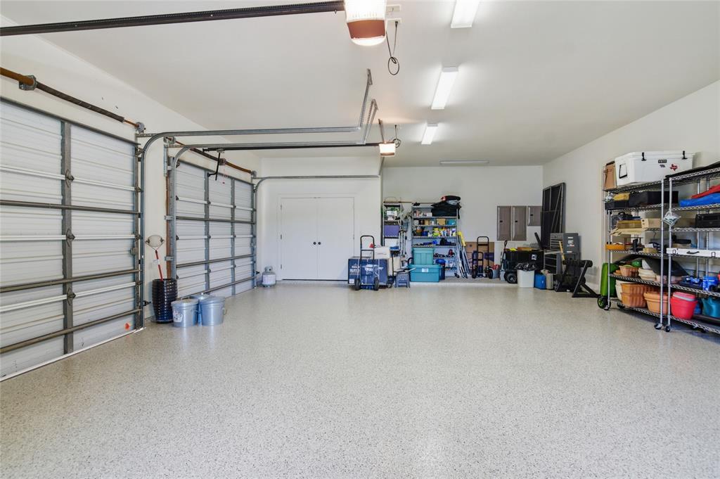 1138 Bancroft Road Keller, TX 76248 - Photo 38 of 39 Spacious two-car garage featuring a speckled epoxy floor coating, two overhead garage doors with automatic openers, flush-mounted fluorescent lighting, and a white interior door