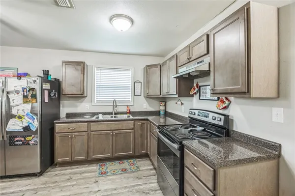 a kitchen with stainless steel appliances granite countertop a sink stove and refrigerator