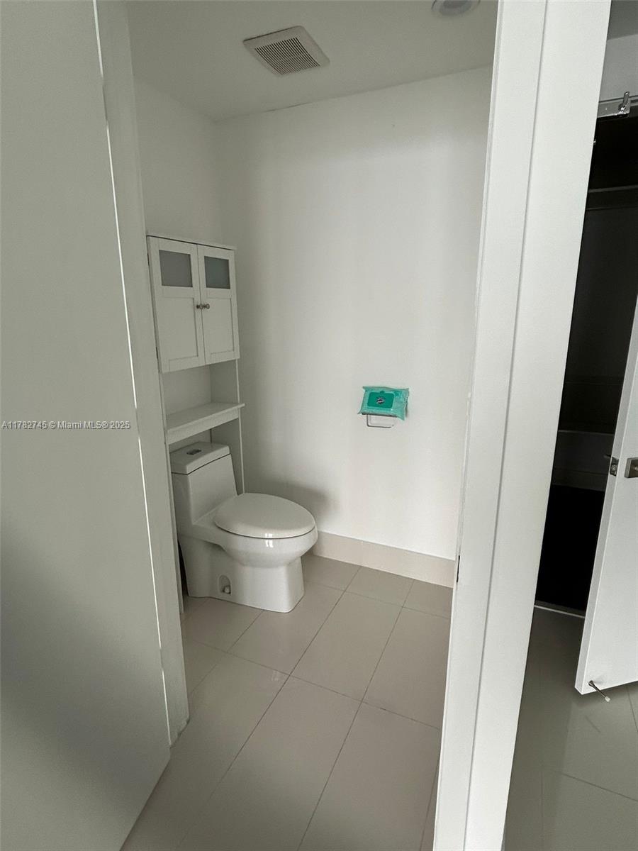 Edgewater Miami, FL 33137 - Photo 4 of 10 a white toilet sitting next to a bathroom sink and a mirror