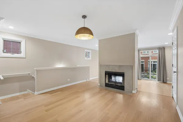 an empty room with wooden floor fireplace and window